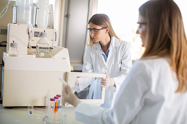 Two people in white lab coats using scientific equipment