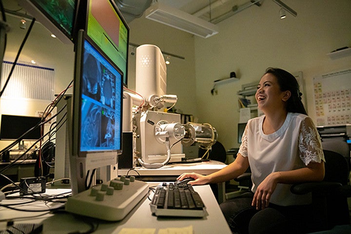 A person smiles while working on a computer in a lab