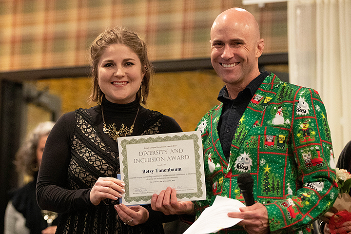 A woman and a man pose while the woman holds up a certificate