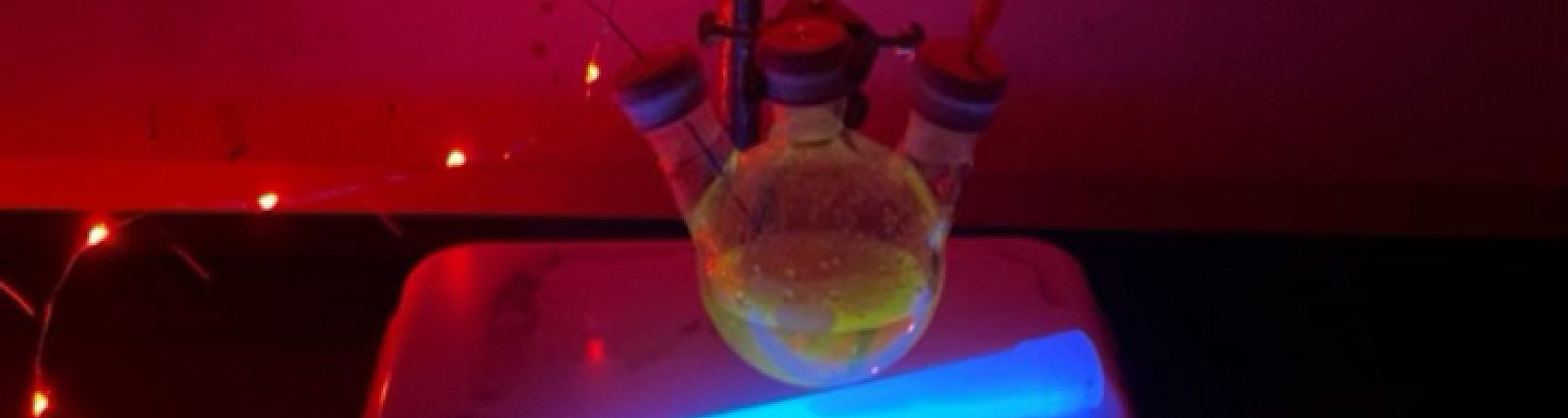 Chemicals lit up in different colors in a darkened lab